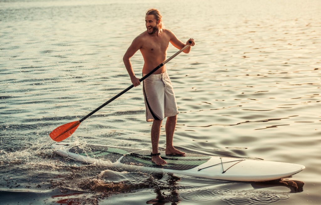 Young man smiling while Stand Up Paddling