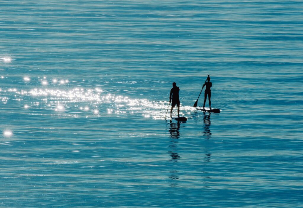 man and woman stand up paddling on the sea, Picture as Symbol for a proper SUP Paddle Technique, Stand Up Paddle Board Tips and Advice, SUP Paddle Technique