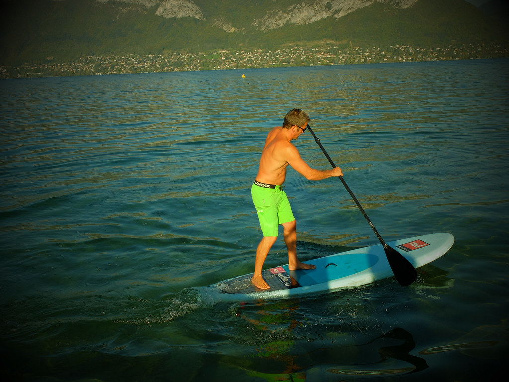 Man Stand Up Paddling on a lake using the Staggered or Step Stance position on the SUP Board. Photo by widiwici