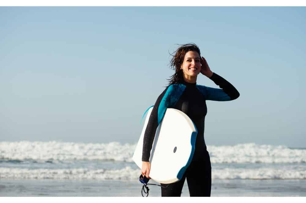 Surfer woman leaving the sea after surfing with bodyboard