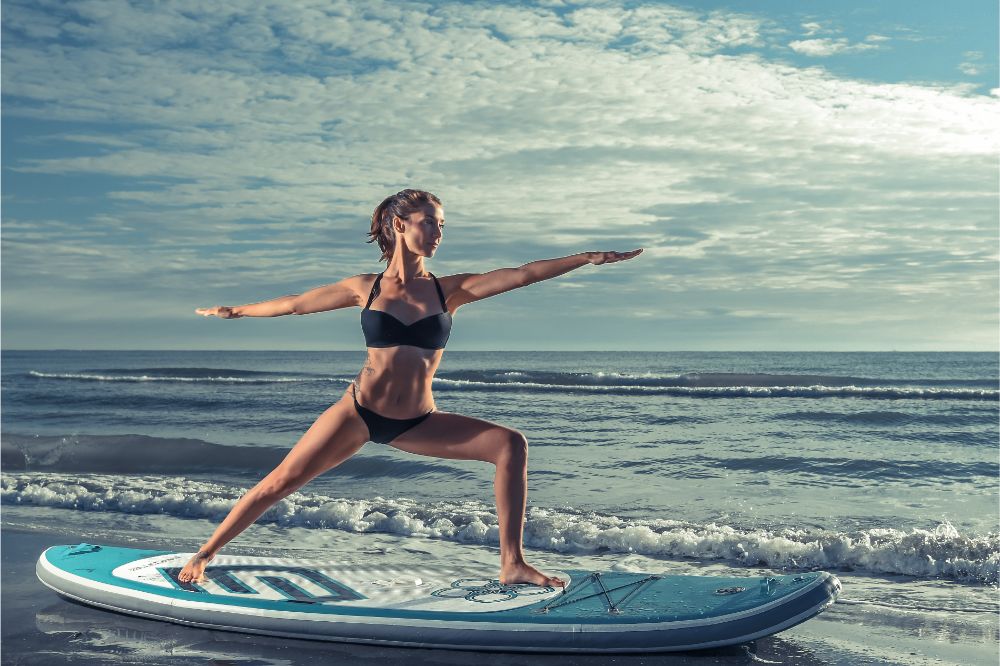  woman practicing SUP yoga at sunrise