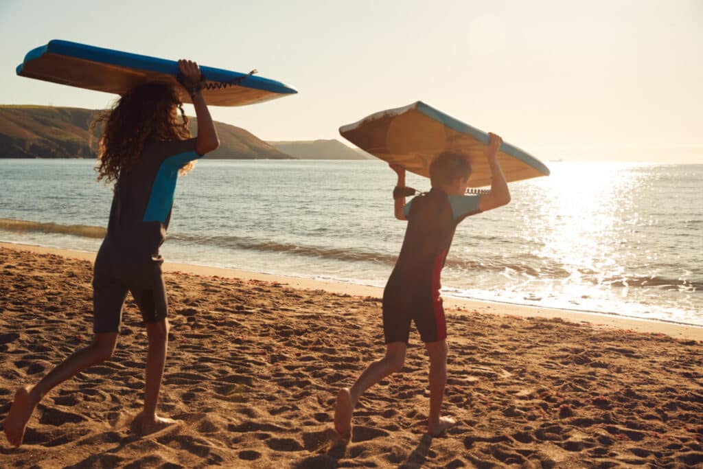 Kids heading to the water for Bodyboarding, article about how to Drop Knee Bodyboard