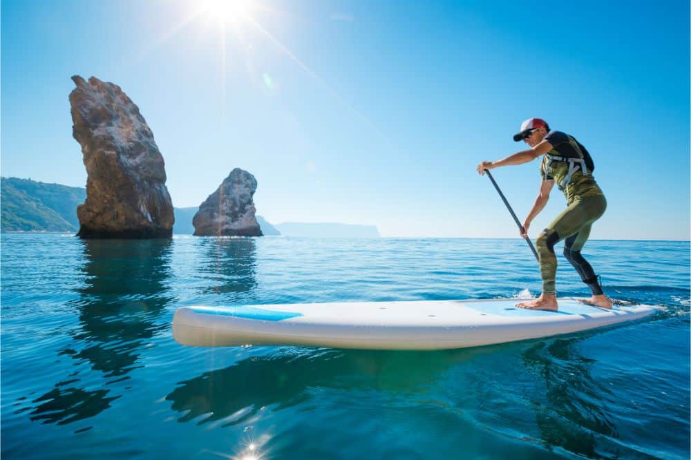 Young man floating on a SUP board, picture used in an article which answers the question Is SUP good for your Back?