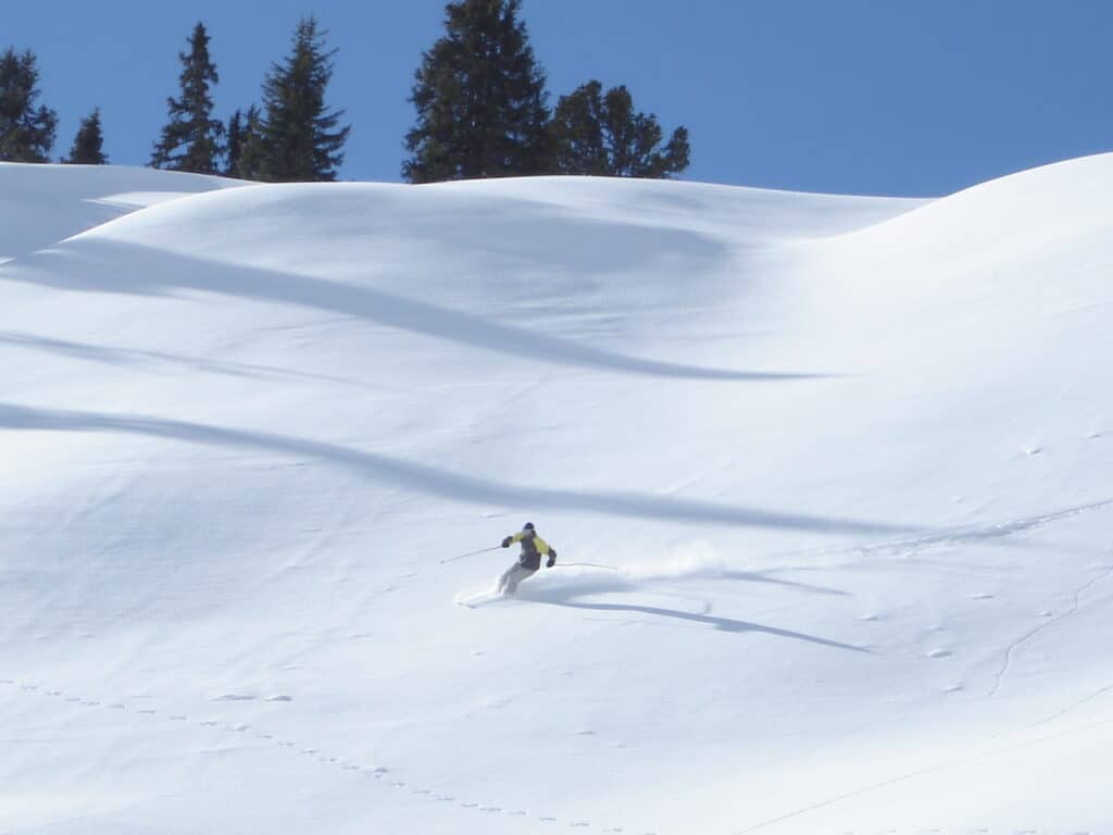Freeride Skifahrer bei einem epischen Powder Turn, Skifahrer beim Tiefschneefahren