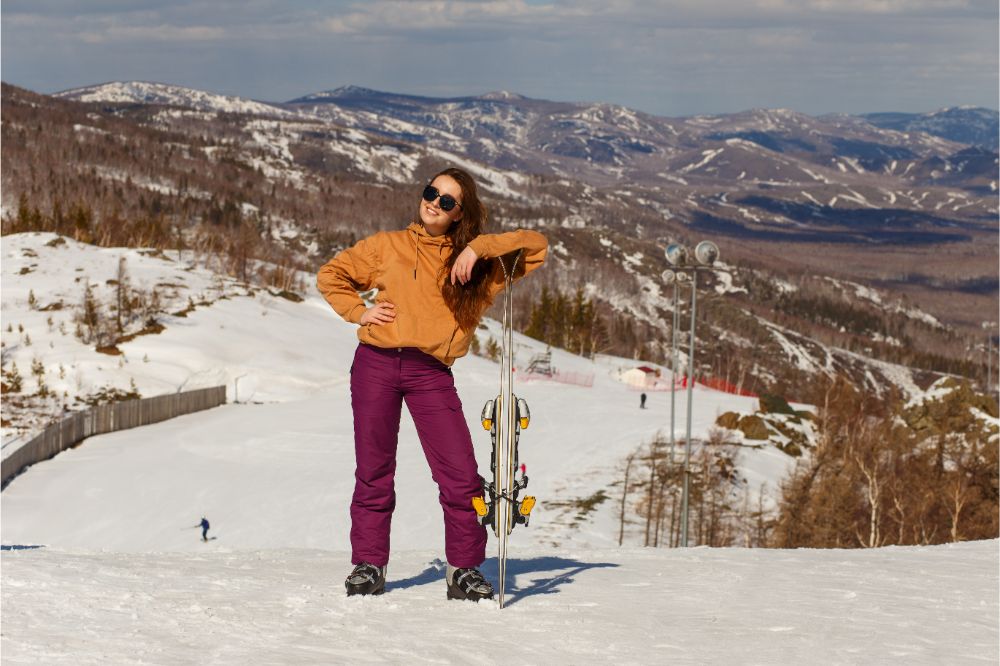 young woman in dark glasses in a hoodie and ski pants