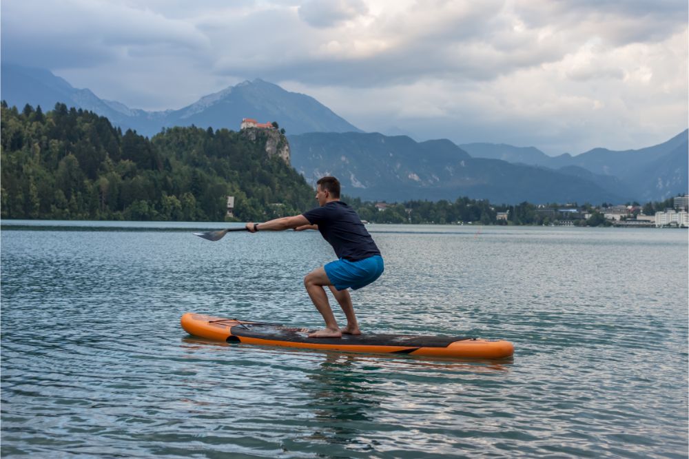 young man exercising on paddle board at the lake, man training his fitness on a Stand-Up Paddleboard, Stand Up Paddle Boarding for Weight Loss