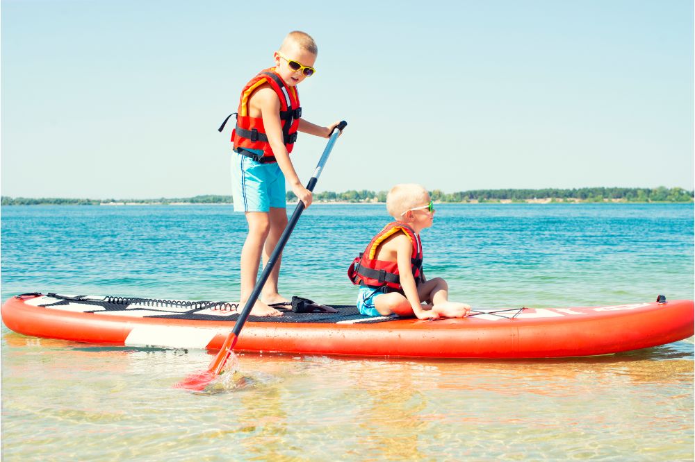 Two brothers swimming on stand up paddle board, two little boys paddling on a Stand-Up Paddle Board, Stand-Up Paddleboarding for Kids