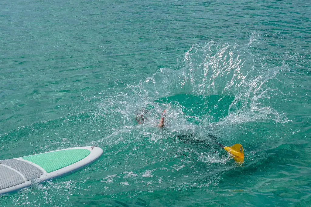 Stand Up Paddle Boarder falling from the SUP Board into the water