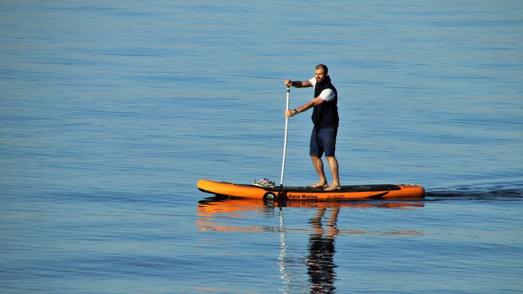 Man on a Stand Up Paddle Board showing a proper SUP Paddle Technique, SUP on a lake