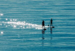 Man and Woman going straight on a stand up paddle board on a lake