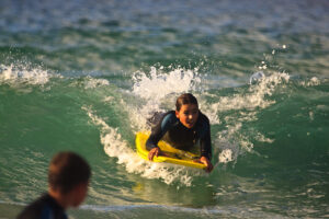 Kid riding a wave on a bodyboard, kids bodyboard, how to find the best bodyboard for kids