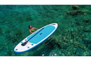 Junge schöne Frau entspannt im Meer auf einem SUP-Board