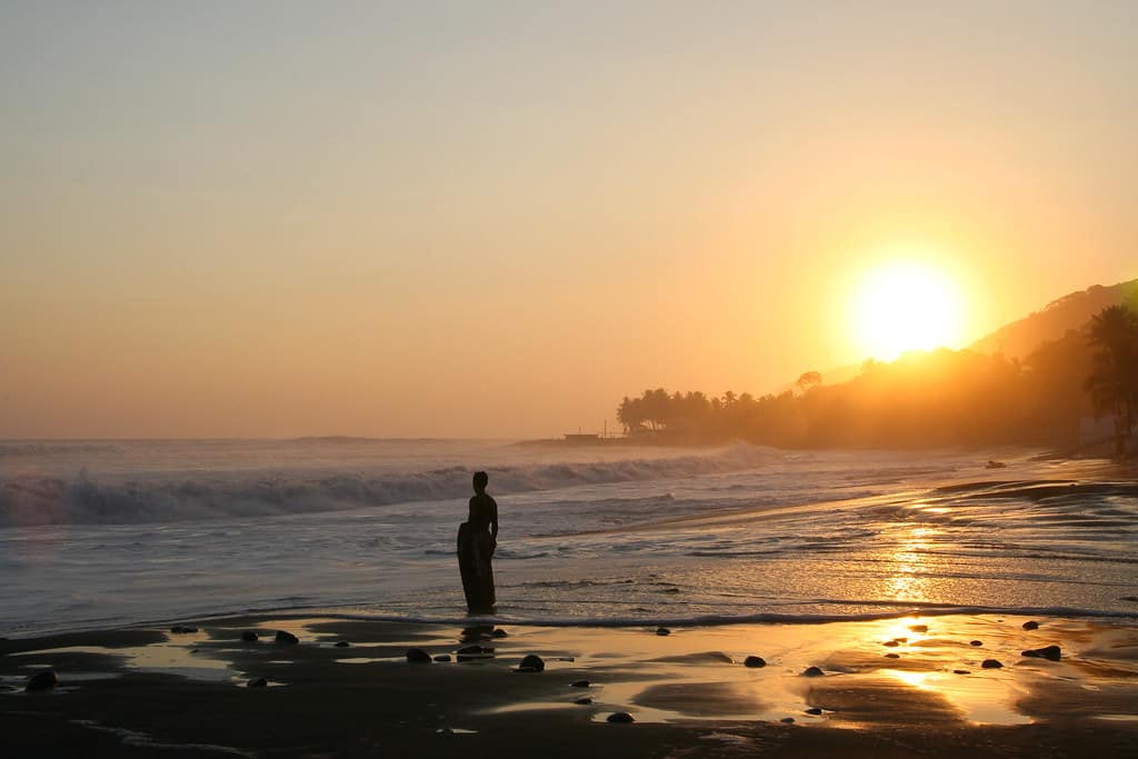 Bodyboarder standing on the beach in sunrise, bodyboarding