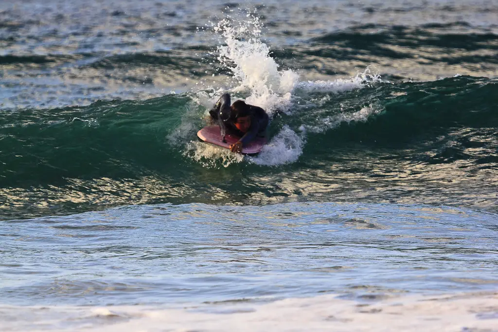 Bild das einen Bodyboarder zeigt der eine Welle surft und dabei in die Richtung der Brechung der Welle surft. Bild das die zweite Phase beim Surfen mit einem Bodyboard zeigt.