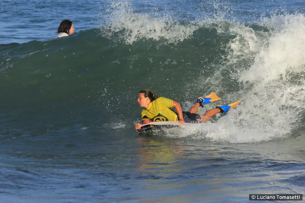 Woman riding a wave with a bodyboard wearing bodyboard fins