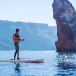 A man fishes on a fishing tackle in the standup paddleboard, SUP fishing, Fishing on a SUP, Man fishing on a stand up paddle board