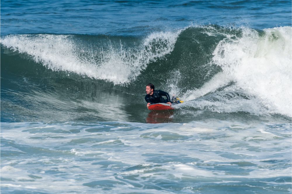 Mann in einem Neoprenanzug beim Bodyboarden