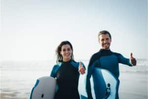 Mann und Frau mit einem Bodyboard und dem Daumen hoch Zeichen