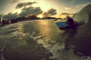 Bodyboarder der eine Welle im Sonnenuntergang surft