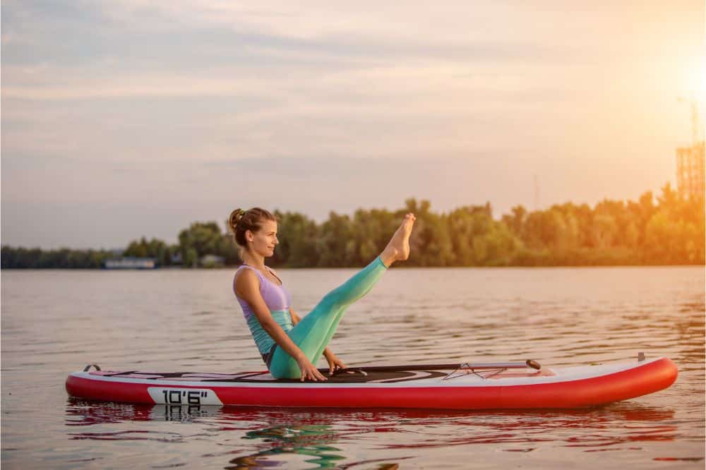 Doing yoga exercise on sup board, Woman doing the Boat Yoga Pose on a Stand Up Paddle Board, Yoga excercise the Boat Pose on a SUP Board