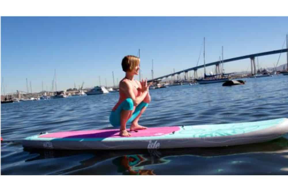 woman doing garland pose on sup, Woman in the Garland Yoga Pose on a Stand Up Paddle Board