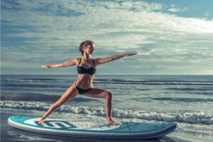 Frau die SUP Yoga im Sonnenaufgang macht