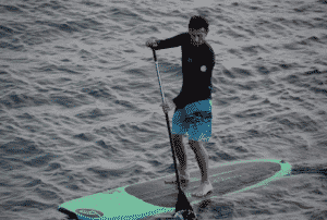 Man doing Touring Paddleboarding on a lake, man on a Touring SUP Board, Man on a Touring Stand Up Paddle Board used in an article explaing what is a Touring SUP Board