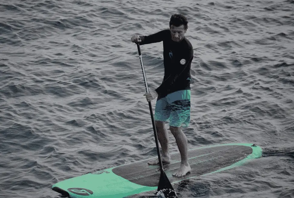 Man doing Touring Paddleboarding on a lake, man on a Touring SUP Board, Man on a Touring Stand Up Paddle Board used in an article explaing what is a Touring SUP Board