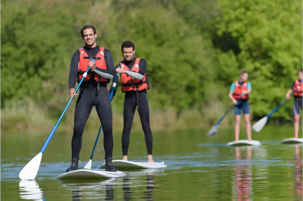 young people stood on paddle boards