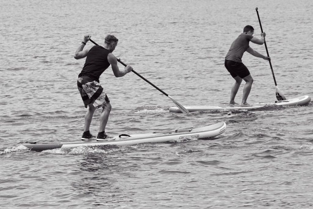 stand up paddling, paddling, Wassersport, zwei Männer beim Touring Paddleboarding die ein Touring Paddleboard oder Touring SUP verwenden, welche für mehr Geschwindigkeit und insbesondere fürs Fitnesstraining mit Stand Up Paddling ausgelegt ist.
