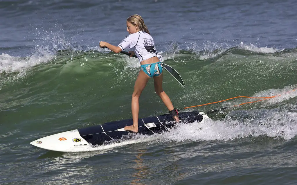 Kid surfing a wave with a Paddleboard using a Paddleboard with Stickers on it