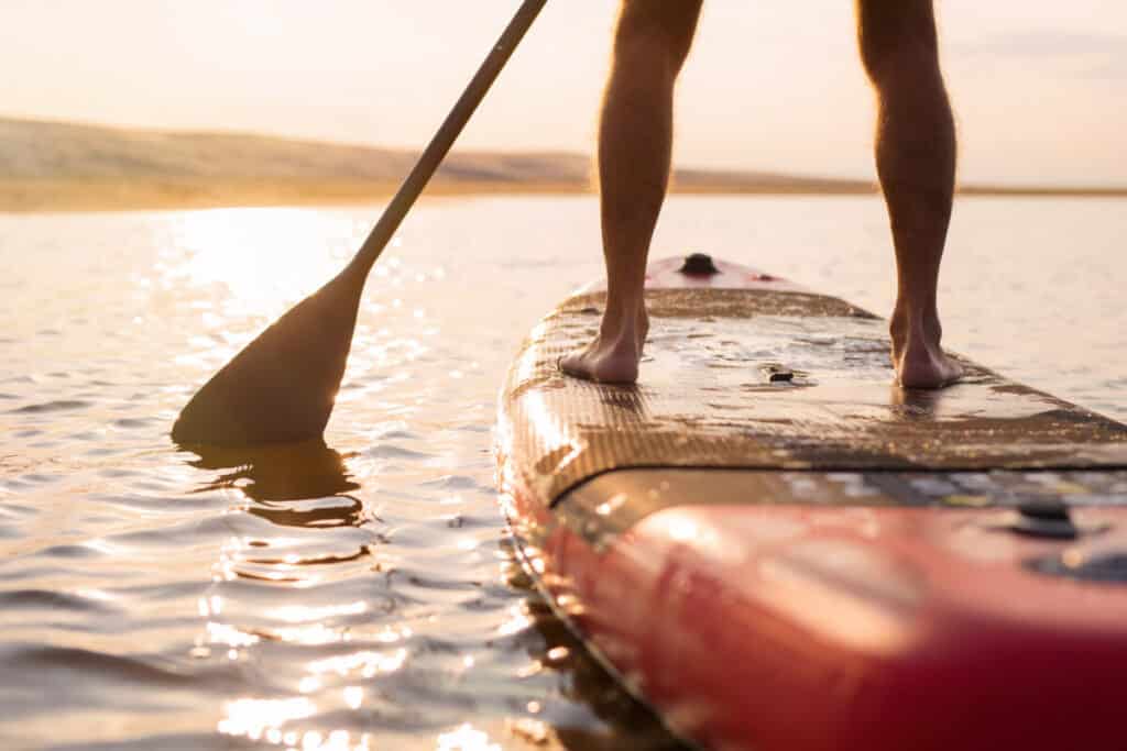 Man standing on a Paddleboard or SUP board in a sunset, man standing on an iSUP Board