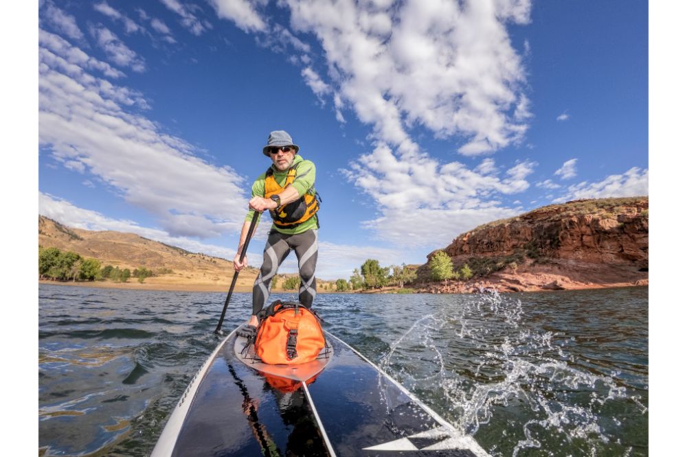 senior man paddling a stand up paddleboard with a Drybag on his SUP Board