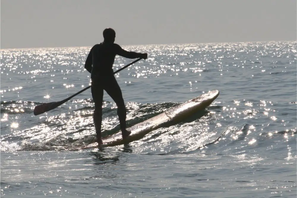 man in wetsuit paddleboarding on a downwind board
