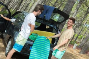 Young men parked in forest getting body boards from van