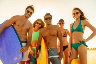 Smiling friends carrying bodyboards having fun on beach