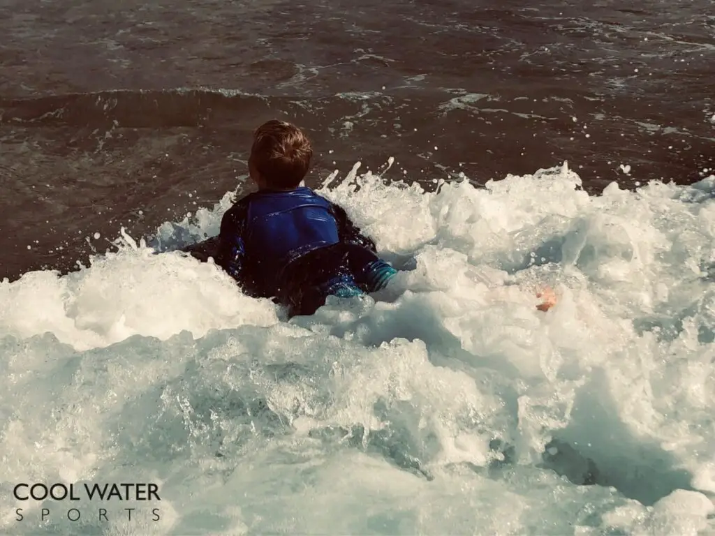 Young boy riding a wave with his bodyboard. Kid bodyboarding in a mushy wave