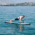 Man doing push-ups while floating on paddle board in the middle of the sea