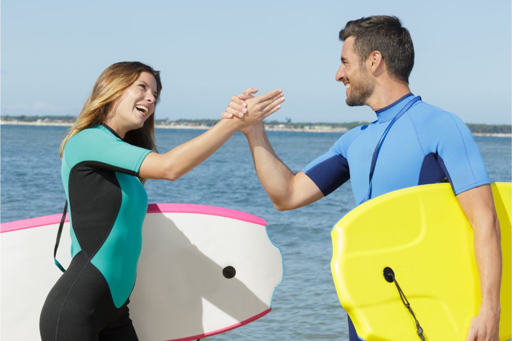surfers couple doing a high five