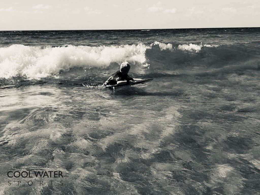 Junge der mit seinem Bodyboard in eine Welle springt Bild das erklärt wie man am besten mit einem Kind Bodyboarding lernt