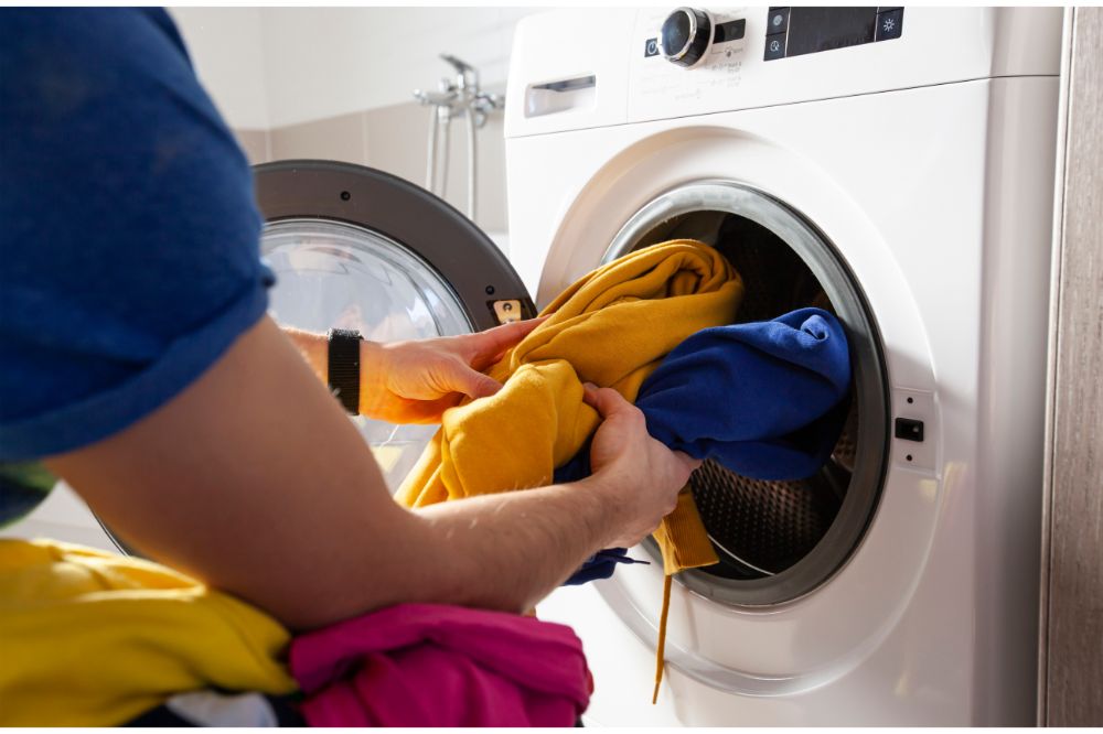 Man loading the washer dryer with clothes