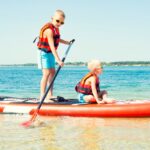 Two brothers swimming on stand up paddle board