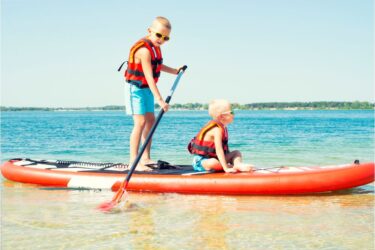 Two brothers swimming on stand up paddle board