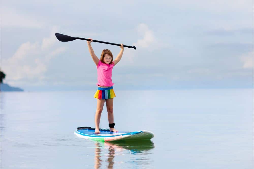 Child on stand up paddle. Water and beach sport, Kid on a SUP Board, Girl on a Stand Up Paddleboard