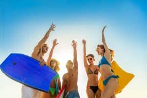 Friends in swimwear carrying bodyboards celebrating fun activity