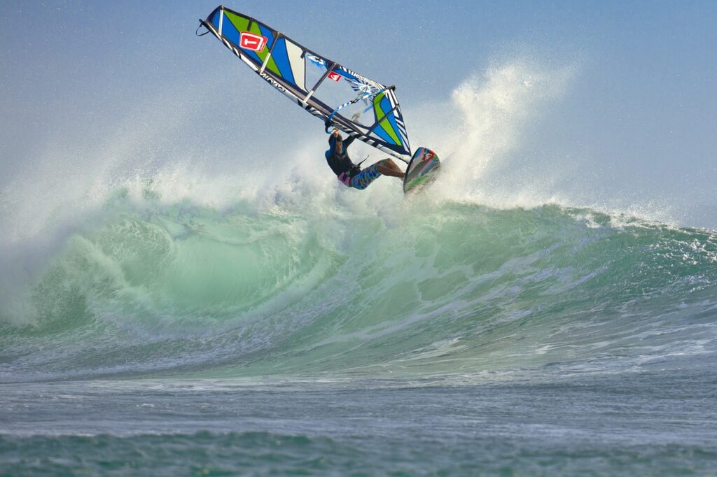 wind surfing, surfer, man riding a hude wave on a windsurf board