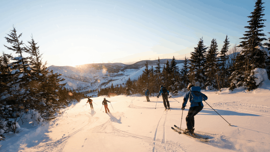 Several people skiing down a ski slope on a beautiful sunny day.