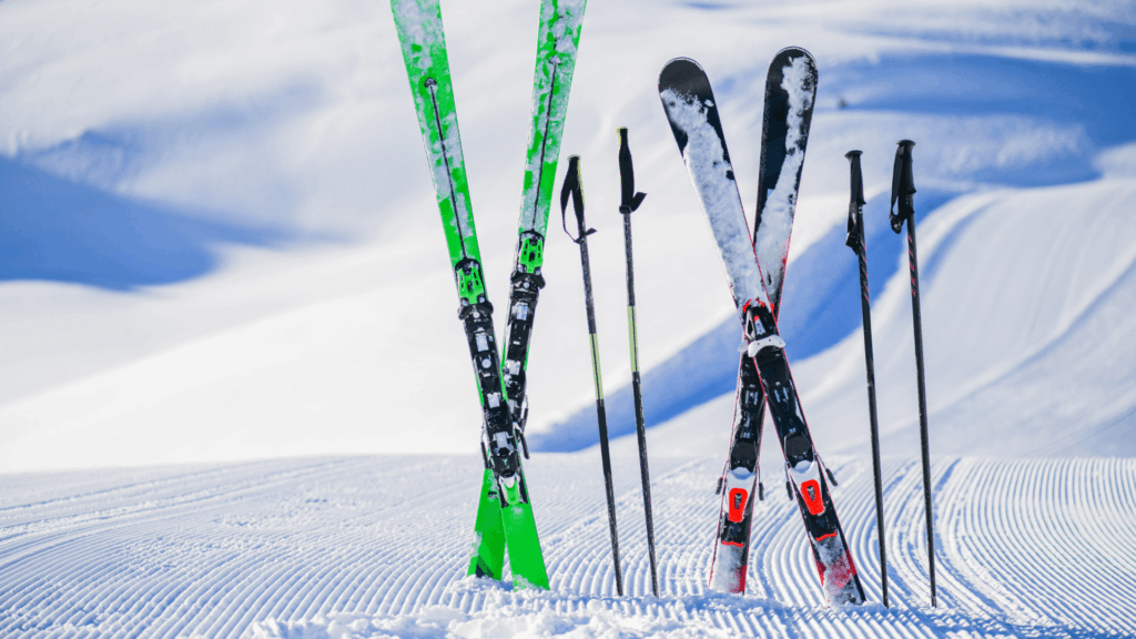 A photo of two sets of skis and poles partially buried in fresh snow.