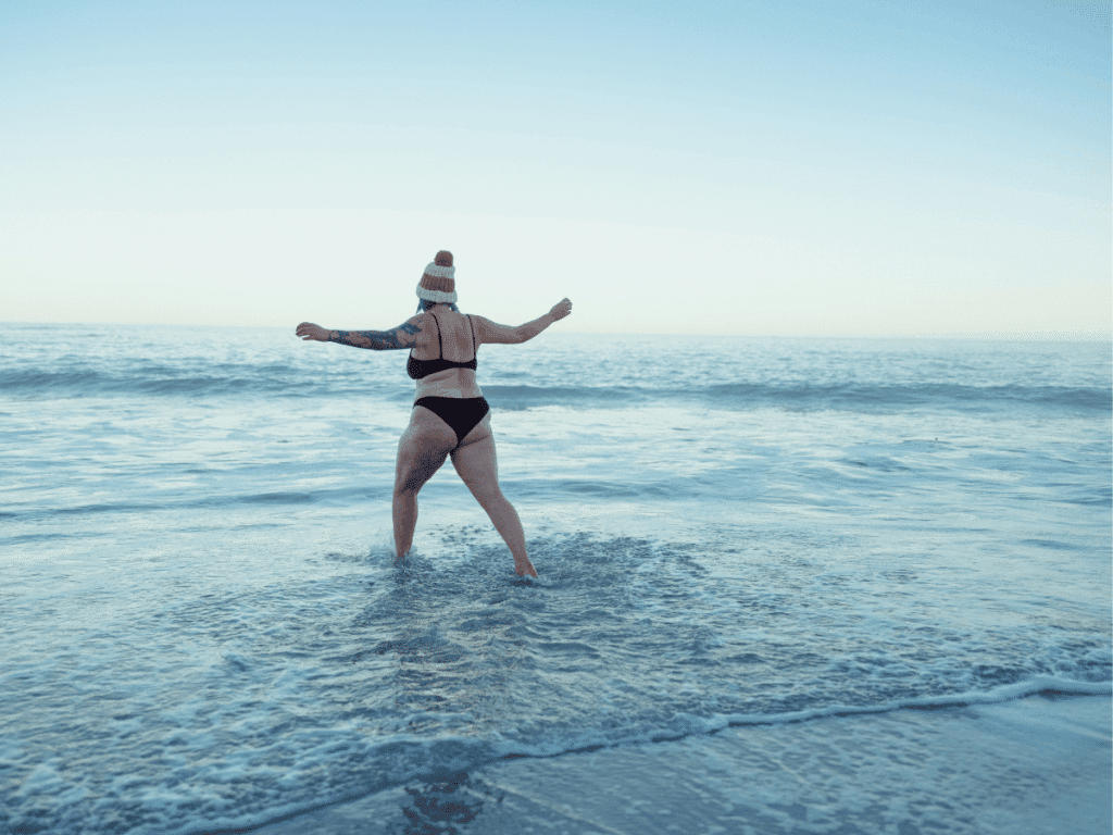 A woman running out into the sea for some cold and saltwater therapy