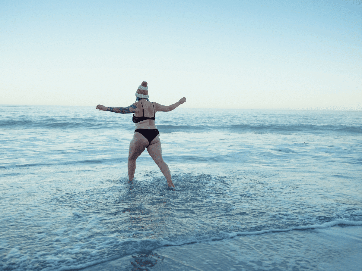 A woman running out into the sea for some cold and saltwater therapy